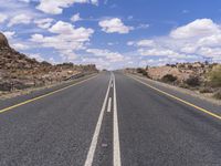 the empty street is on the rocky hill side and yellow paint shows the line of a curving road