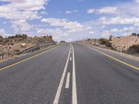 the empty street is on the rocky hill side and yellow paint shows the line of a curving road