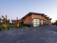 this is a driveway in the middle of a large wooden home with glass doors and an outdoor bench