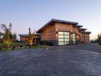 this is a driveway in the middle of a large wooden home with glass doors and an outdoor bench