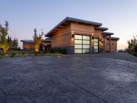 this is a driveway in the middle of a large wooden home with glass doors and an outdoor bench