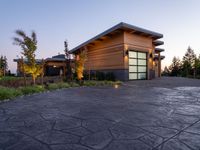 this is a driveway in the middle of a large wooden home with glass doors and an outdoor bench