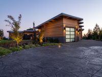 this is a driveway in the middle of a large wooden home with glass doors and an outdoor bench