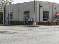 a corner restaurant in the city with tables outside and a car parked on the side