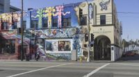 the corner is covered in a variety of murals, including a man walking next to a building with colorful mural