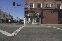 the intersection of an empty street with buildings in the background and people walking on the sidewalk