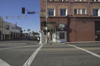 the intersection of an empty street with buildings in the background and people walking on the sidewalk