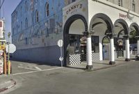 a restaurant with a large mural on the side of it's building with arches and columns