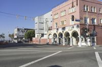 a corner with cars waiting at the intersection near buildings and streets with a flag flying above