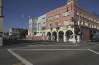 a corner with cars waiting at the intersection near buildings and streets with a flag flying above