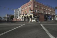 a corner with cars waiting at the intersection near buildings and streets with a flag flying above