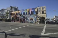 an intersection with a painting on a building and pedestrians crossing the street in front of it