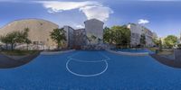 a photograph with a 360 - ball in it of basketball court and city buildings around