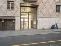 scooter parked in front of a building near an entrance way with a closed glass door