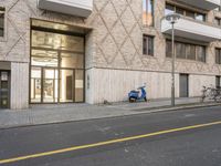 scooter parked in front of a building near an entrance way with a closed glass door