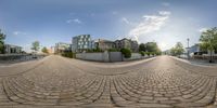 there is a fish - eye view of a street with stone blocks and houses in the background