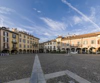 the courtyard is full of buildings and benches in each side of it and the clouds are clear