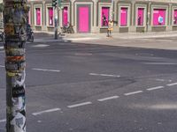 a pole with graffiti on it and a pink door and sign on it at an intersection