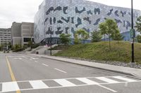 a car parked near the side of a city street that has a silver building in the background