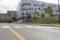 a car parked near the side of a city street that has a silver building in the background