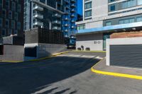 there is a paved street next to tall buildings with glass windows in the background and the building is painted white