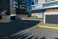 there is a paved street next to tall buildings with glass windows in the background and the building is painted white