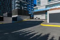 there is a paved street next to tall buildings with glass windows in the background and the building is painted white