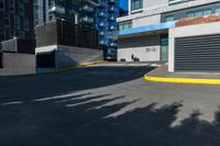 there is a paved street next to tall buildings with glass windows in the background and the building is painted white