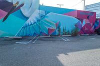 the parking lot is adorned with colorful street art like a humming bird, and features a geometric design