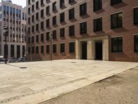 the courtyard of a building in an urban neighborhood is empty with cars parked in the distance