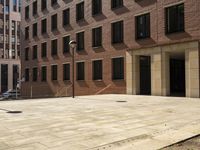 the courtyard of a building in an urban neighborhood is empty with cars parked in the distance