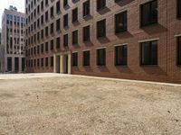 the courtyard of a building in an urban neighborhood is empty with cars parked in the distance