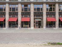 two tall buildings with red awnings in front of them and a sidewalk in front