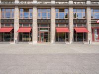 two tall buildings with red awnings in front of them and a sidewalk in front