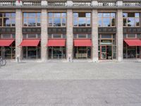 two tall buildings with red awnings in front of them and a sidewalk in front