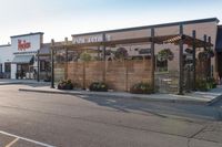 a store front with wood privacy screens and a car parked outside it, on the street side