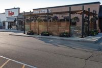 a store front with wood privacy screens and a car parked outside it, on the street side