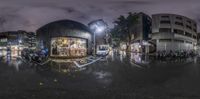 a fisheye lens photo of a street at night with a traffic light and lots of people