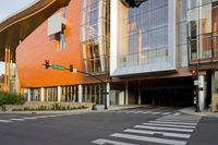 an orange building with lots of windows and a crosswalk at a traffic light on the street