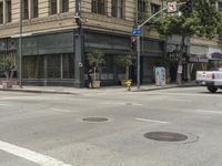 people crossing the street at a cross walk under traffic lights, in front of a brown building