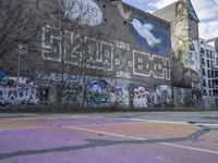 a basketball court in front of a building has graffiti on it with the words'harlem alley all over the wall