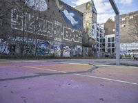 a basketball court in front of a building has graffiti on it with the words'harlem alley all over the wall