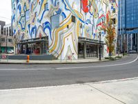 a person standing on the side of a street next to a building with brightly colored walls