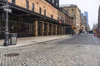 there is a street with brick walkways on both sides of it and some tall buildings behind it