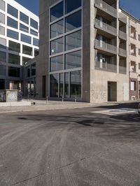 a view of a street through a windowed glass building towards a parking lot with parked bikes