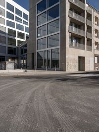 a view of a street through a windowed glass building towards a parking lot with parked bikes