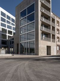 a view of a street through a windowed glass building towards a parking lot with parked bikes