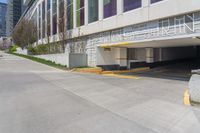 the view of a parking garage in front of a high rise building on an empty street