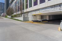 the view of a parking garage in front of a high rise building on an empty street