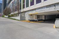 the view of a parking garage in front of a high rise building on an empty street